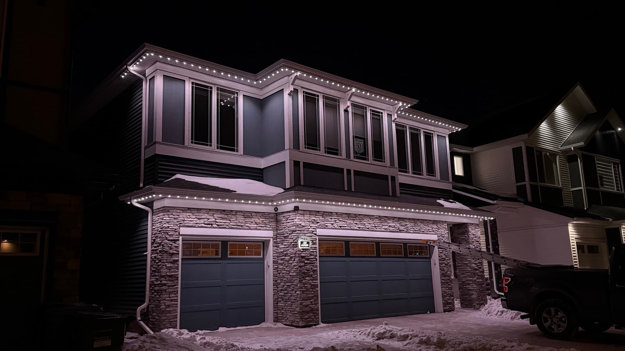Calgary front elevation at night with clean, even permanent roofline lighting.