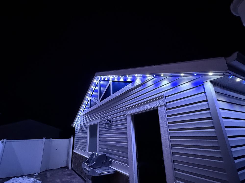 Blue and white Luminair lighting along the rear gable and eaves of a home at night
