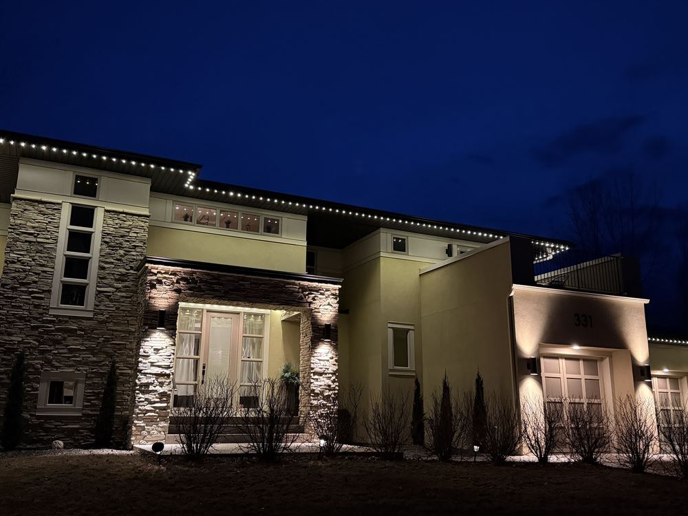 Cool white Luminair lighting along a low prairie-style roofline with the entry and garage lit below