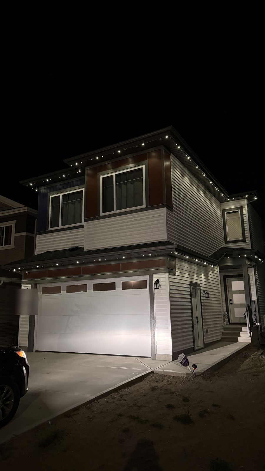 Luminair warm white architectural permanent lights on a new-build vinyl-sided home in Calgary at night