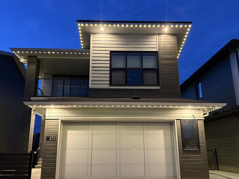 Modern home lit straight on with warm white Luminair roofline lighting against a deep blue sky
