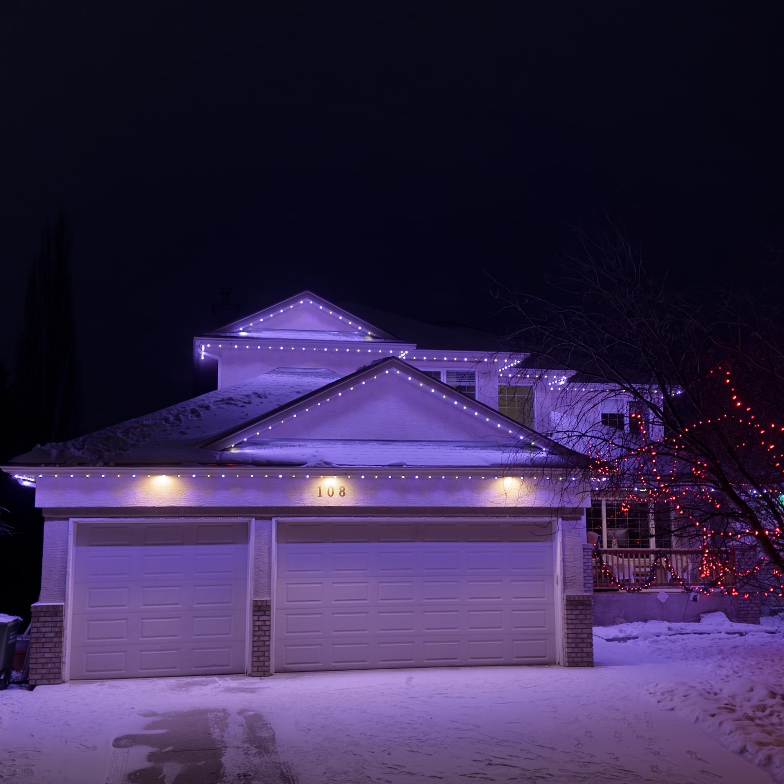 The same two-storey home switched from red and green to a purple and white scene in the app, washing the gables and garage