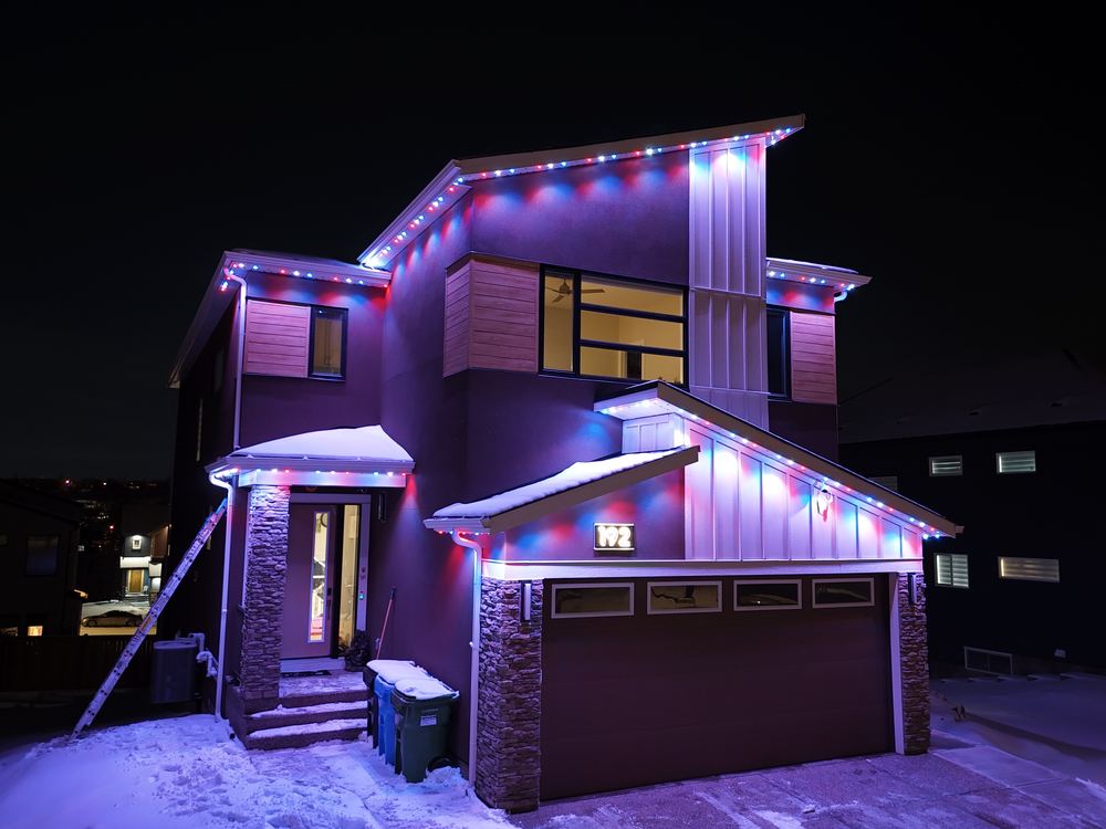 A modern home running a red, white and blue Luminair scene across every roofline and gable