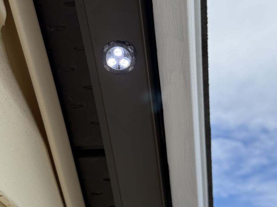 Close-up of a lit Luminair LED module in brown colour-matched track, showing the sealed triple-diode array