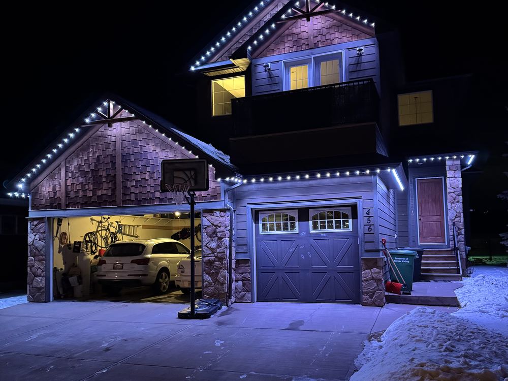 Two shingled gables and a garage outlined in cool white Luminair lighting on a winter evening