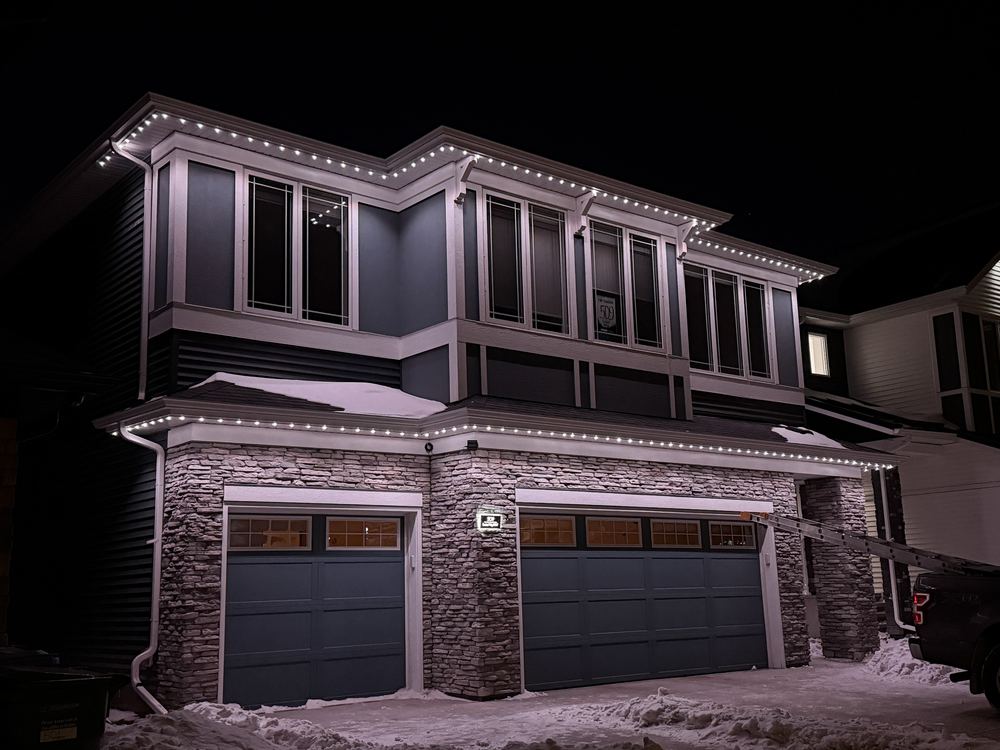 Cool white Luminair lighting across the rooflines of a stone-fronted home with a double garage