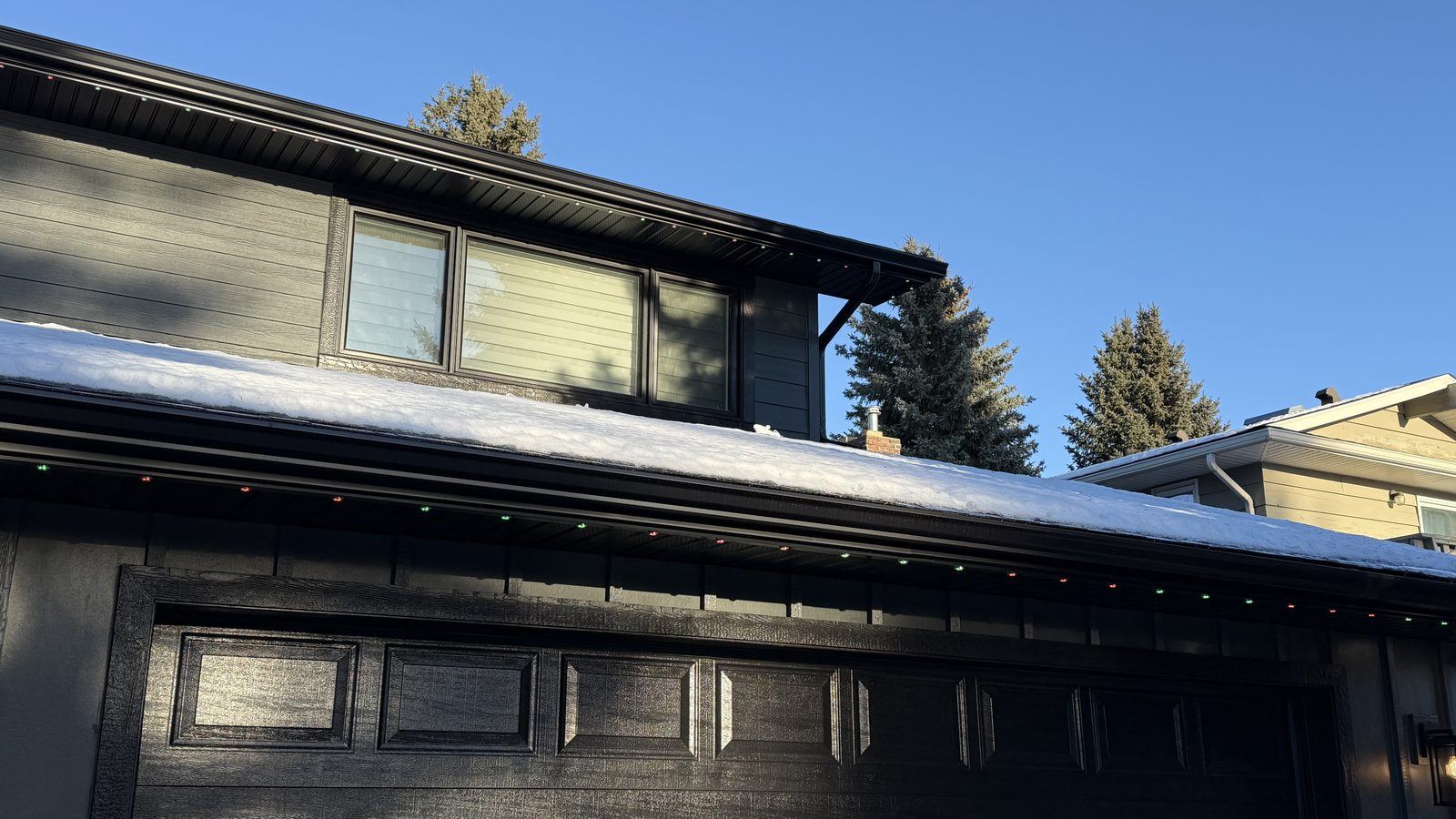 Luminair track colour-matched to a black soffit and fascia in daylight, the unlit fixtures nearly invisible against the dark trim