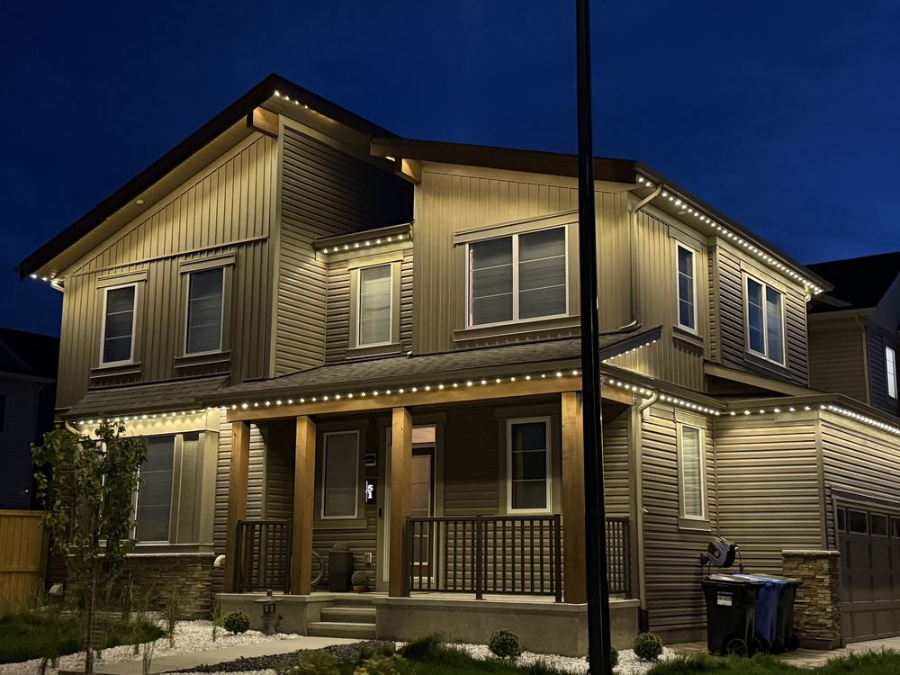 Warm white Luminair lighting tracing the roofline, porch and gable of a two-storey home at dusk